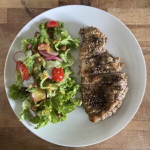 plate of mediterannean chicken with salad dressed with a tahini, honey, mustard and with tomatoes and almonds