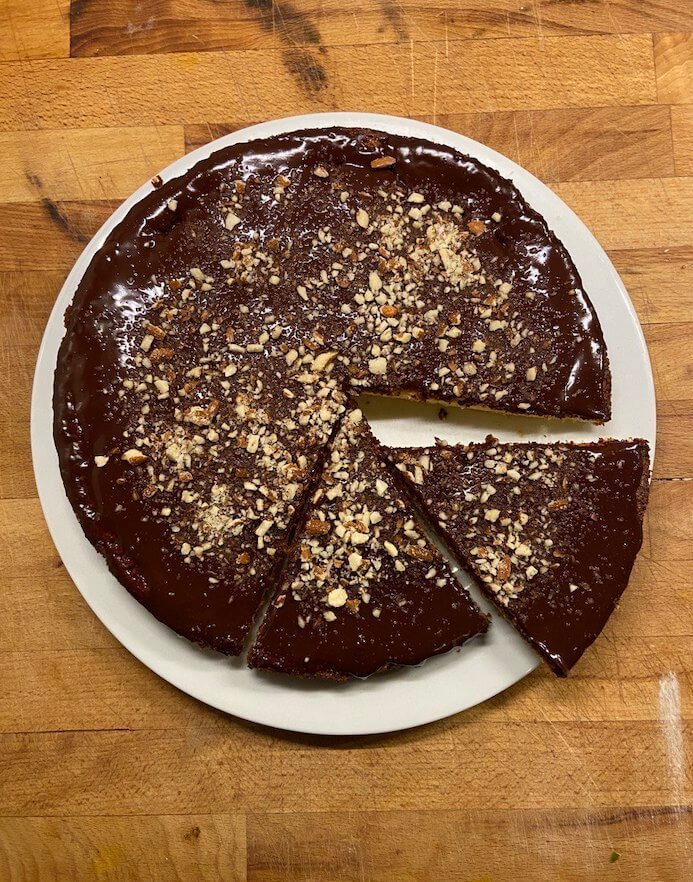 Orange & Almond Cake sliced, topped with chocolate ganache and crushed almonds 